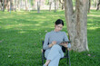 © Thitisak - Asian woman sitting using laptop, working in a park