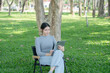 © Thitisak - Asian woman sitting using laptop, working in a park