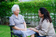 © manassanant - Caregiver help Asian elderly woman disability patient sitting on wheelchair in park, medical.