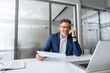 © Stock 4 You - Positive financial specialist senior man working on laptop computer in office, having cell phone call. Mature businessman professional using pc, analysing business project, holding report document