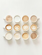 © artpoizzy - A minimalist grid of coffee cups showcasing contrasting milk tones, from dark espresso to light tea beige, on a clean white background. Natural textures, no text, pure aesthetic beauty