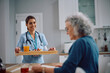© Drazen - Happy nurse serving food to her senior patient during home visit.