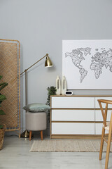 Poster - Dresser with different decor, lamp and pouf near grey wall indoors. Interior design