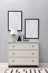 Poster - dresser with table lamp and bookend near light grey wall in room. interior design