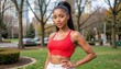 © Namwan - A confident young black African ethnic woman wearing sportswear top standing in a city park looking at the camera Close up portrait using e commerce ready stock photo digital content fashion photograp