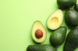 © New Africa - Whole and cut avocados on light green background, flat lay. Space for text