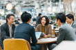 © boyhey - A group of Japanese business people meeting and discussing in an office.