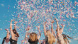 © Довидович Михаил - High school students celebrating graduation by throwing colorful confetti under a sunny blue sky
