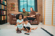 © chokniti - Heartwarming family moment as an African American father and daughter share playful time together on the couch, surrounded by love, laughter, and the warmth of home, while mom gently looks on with joy