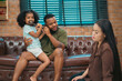 © chokniti - Heartwarming family moment as an African American father and daughter share playful time together on the couch, surrounded by love, laughter, and the warmth of home, while mom gently looks on with joy