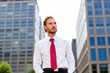 © Minerva Studio - Businessman looking up posing between skyscrapers