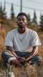 © liliyabatyrova - A man sits cross-legged on a grassy field, eyes closed in deep meditation. The warm glow of golden hour highlights his serene expression, surrounded by nature's beauty.