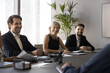 © fizkes - Successful negotiation. Happy smiling diverse gender age businesspeople investors executives sit at boardroom table listen to speaker agree with profitable business offer satisfied with finance report