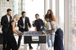 © fizkes - Team spirit. Overjoyed excited diverse corporate workers business partners gather in office recreation area around foosball table supporting cheering for female colleagues players having fun together