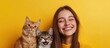 © redflower - Close-up studio shot of a woman smiling warmly with two cats nestled against her.