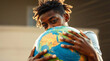 © SvitlanaKvet - A dynamic composition showcases an Afro-American eco-activist student hugging the globe. Strong, hard light creates harsh shadows and blurred lines, capturing the action.jpg