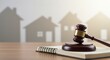 © Neuroillustrator3033 - Legal gavel resting on open notebook with subtle house silhouettes in the background, symbolizing real estate law and justice