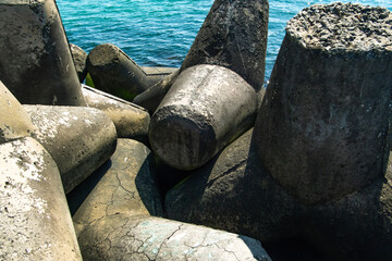 Fototapete - Large, weathered concrete tetrapods create a protective barrier along the coast