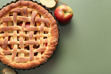 Wall Mural - baking dish with tasty homemade apple pie and fruits on green background