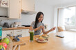 © Charlie's - Asian Girl  eating Thai food in kitchen counter Home delivery food feeling happy 