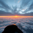 © Ann - Aerial view from cockpit during sunrise over clouds with ocean reflection.