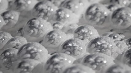 Wall Mural - close-up video of shiny silver spheres on a textured surface, shot from a low angle, creating a futu