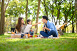 © Prathankarnpap - Happy family enjoying outdoor camping picnic with food and guitar music under trees