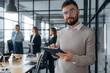© standret - Handsome man is standing. Business people are working in the office