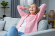 © zinkevych - Smiling mid aged woman in pink shirt looking contented while spending time at home