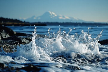 Aufkleber - Beautiful ocean waves splashing against rocky shoreline at sunset with snow-capped mountains in the background