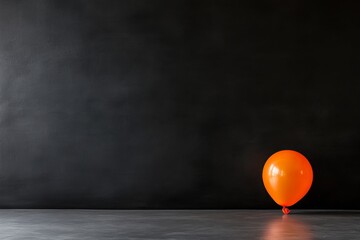Leinwandbilder - An orange balloon floats in front of a matte black background, creating a modern aesthetic with faint reflections and ample copy space for promotional text