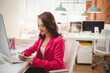 © WavebreakMediaMicro - Asian woman using smartphone at white desk in open-plan office, with monitor and colored pencils