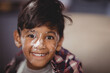 © wavebreak3 - Indian boy smiling at camera at home, showing white flour on face and plaid shirt
