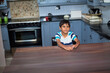 © wavebreak3 - Boy child sitting at wooden dining table in modern kitchen, with tiled backsplash and toaster