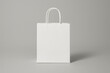 © Ali - Minimalist White Paper Shopping Bag with Handles Standing on Gray Background for Branding and Packaging Design Mockup