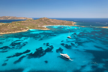 Wall Mural - aerial view of luxury yachts and boats on blue sea, beautiful island on summer sunny day. sandy beac