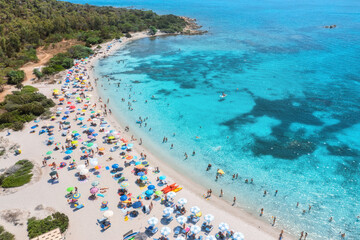 Wall Mural - aerial view of colorful umbrellas on sandy beach, swimming people in blue sea at sunset in summer. s