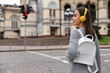 © New Africa - Young woman waiting at traffic lights to cross street