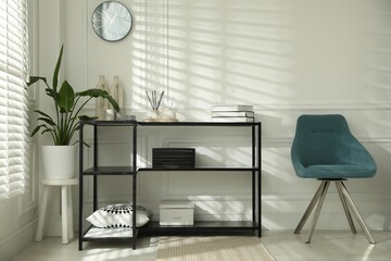 Poster - Console table with different decor and chair near white wall indoors. Interior design