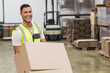 © WavebreakMediaMicro - Man carrying stacked cardboard boxes in warehouse, with forklift and wooden pallets behind