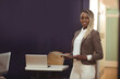 © Wavebreak Media - African American woman standing on right of modern office, holding tablet with laptop, copy space