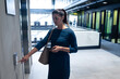 © Wavebreak Media - Businesswoman pressing elevator call button at office lobby, holding smartphone and bag, copy space
