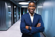 © Wavebreak Media - African American man standing confidently in office hallway, wearing navy suit and smartwatch