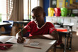 © Wavebreak Media - African American child writing in elementary school classroom with pencil and open notebook