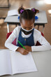 © Wavebreak Media - African American child writing math in notebook in elementary classroom, with green pencil