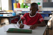 © Wavebreak Media - African American boy writing at student desk in elementary classroom, using open notebook, teal pen
