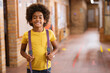 © Wavebreak Media - Child boy standing in school hallway, holding purple backpack straps and smiling