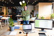 © Wavebreak Media - Mature adult man standing at center of open plan office, among desks, laptops and potted plants