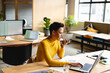 © Wavebreak Media - African American woman typing on laptop while speaking on smartphone at coworking desk, with papers