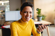 © Wavebreak Media - Young adult male office worker sitting at wooden desk in office space, using smartphone and smiling